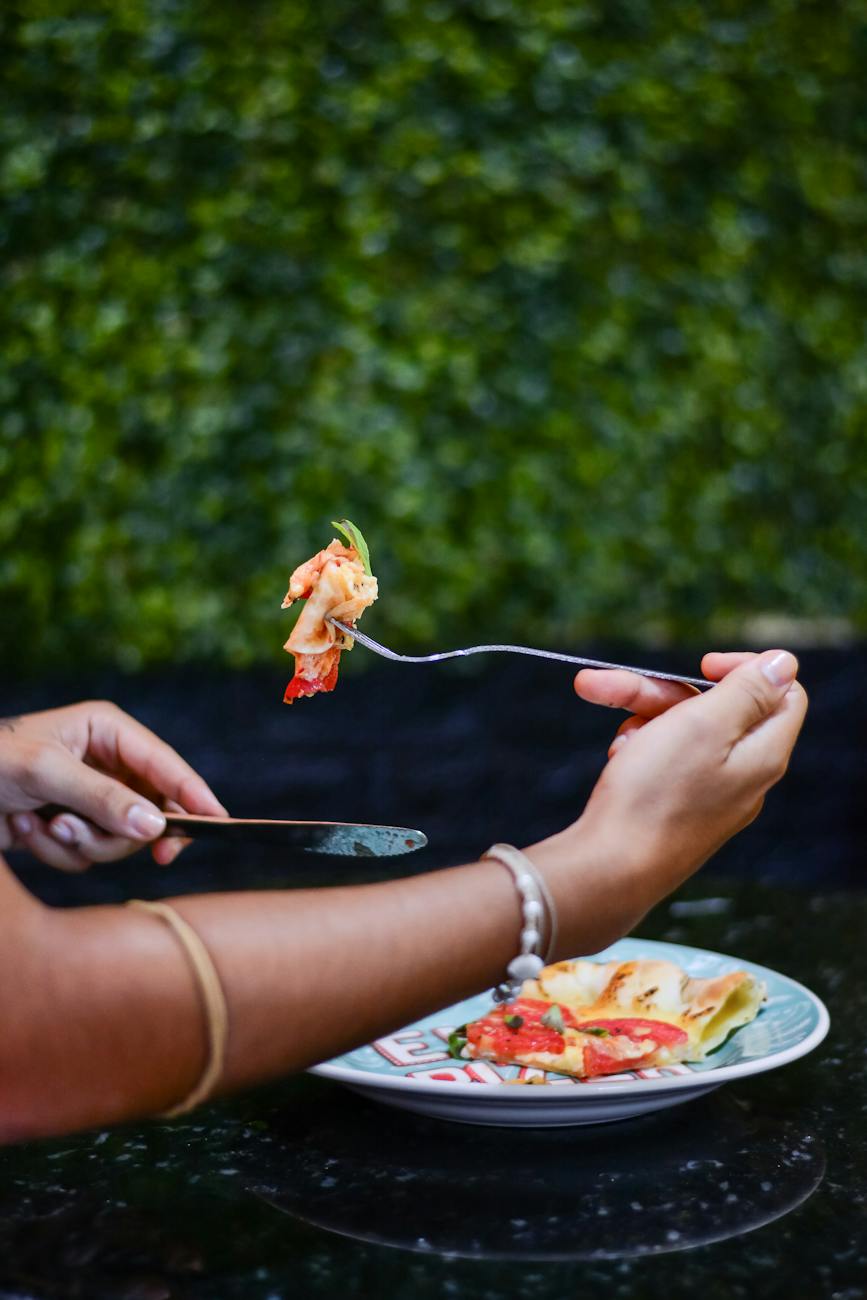 hands holding pizza on fork